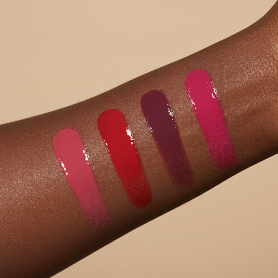 Four pigmented vegan liquid blush swatches on a dark skin arm against a beige background