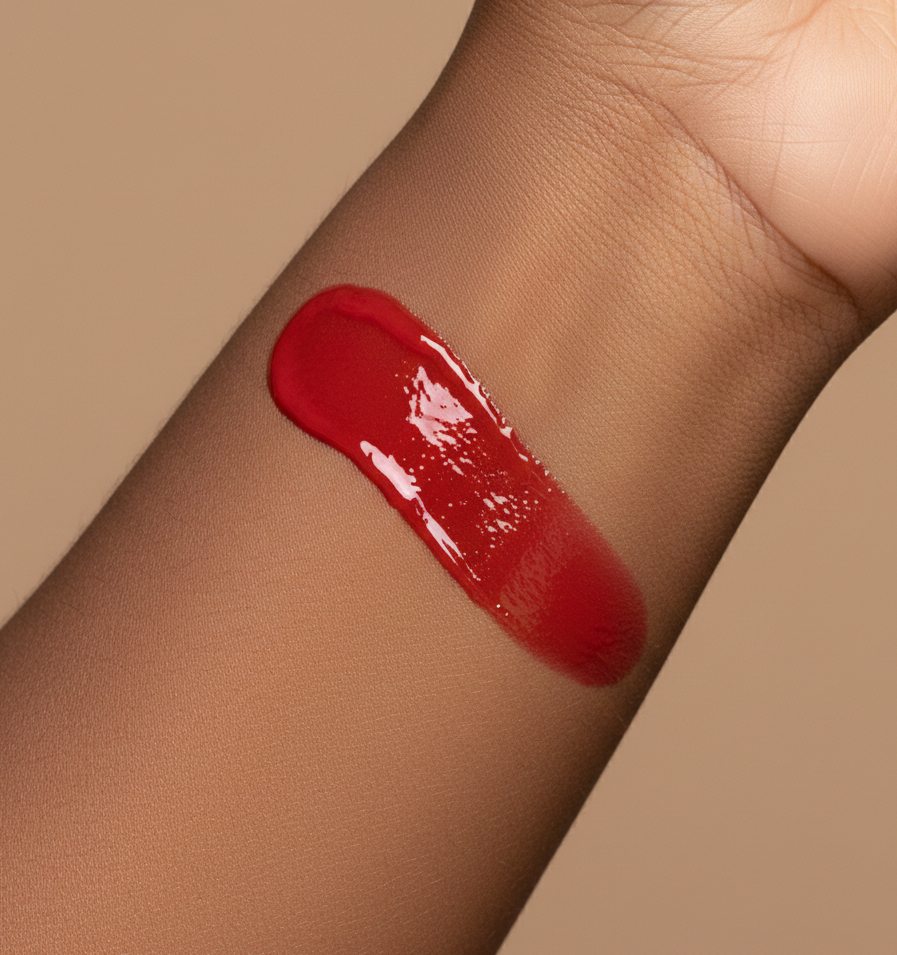 Red vegan lip gloss swatch on a person's arm against a beige background