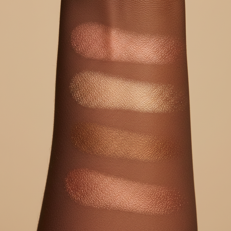 Swatches of 4 pigmented highlighter shades on a person's arm against a beige background