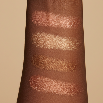 Swatches of 4 pigmented highlighter shades on a person's arm against a beige background