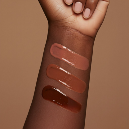 Vegan nude creamy lip gloss swatches on a person's arm against a brown background